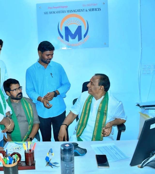 Visitors at the Sri Mokshitha Management and Services office beneath the company sign